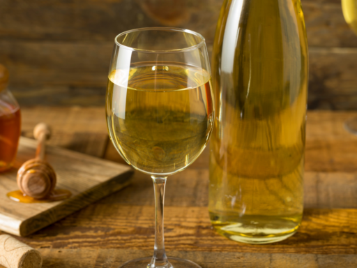 Bottle of mead with two glasses and jar of honey.